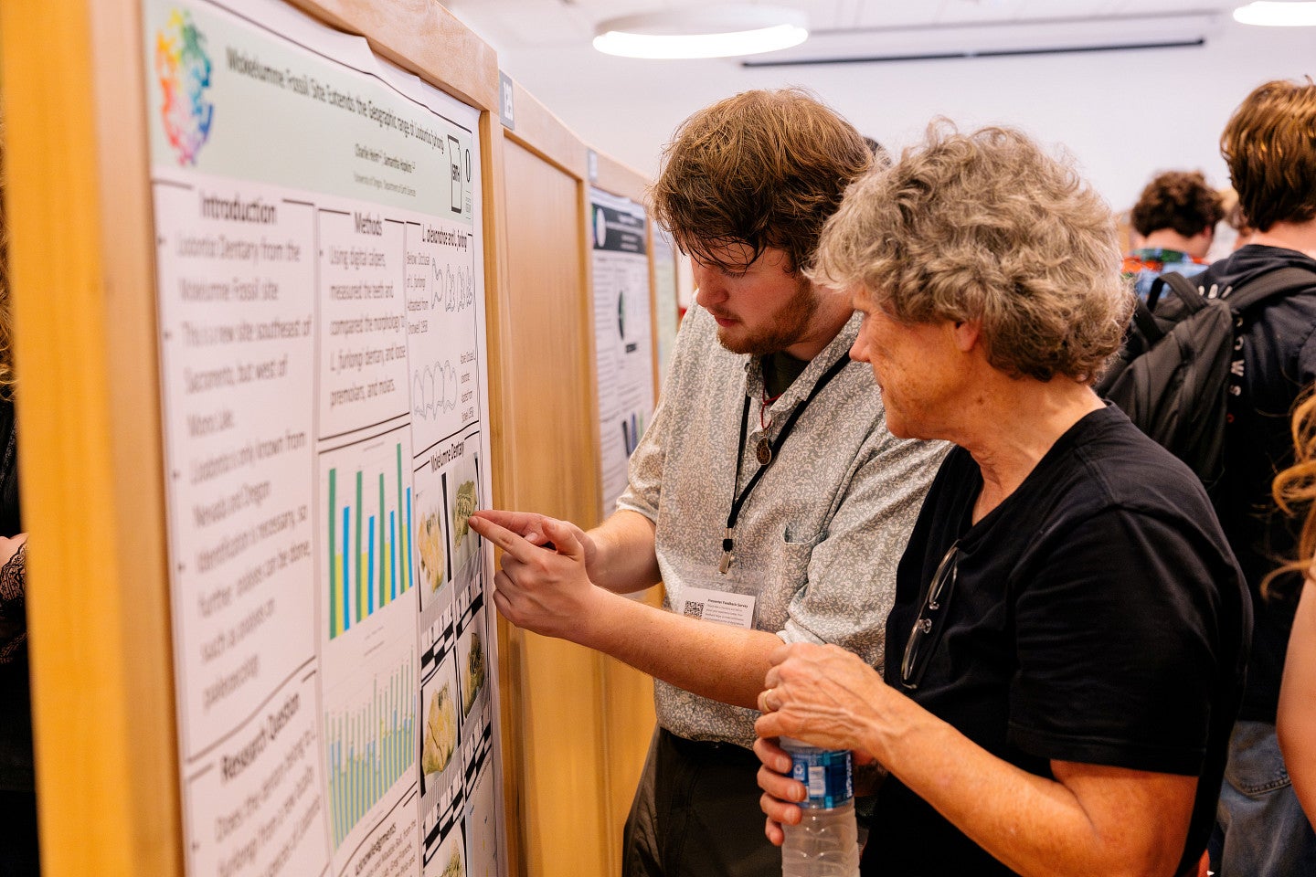 Undergraduate presenter explaining his poster to an attendee