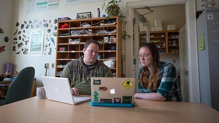 Two researchers examining data on laptop computers