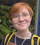 Delilah Fisher has short red hair and glasses