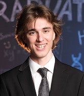 Nikita (Nick) Klepikov has medium brown hair and wears a suit and tie