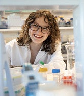 Chloe Baker wearing a lab coat and working in a lab