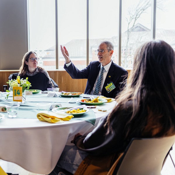 provost chris long talks to table of people at PURA luncheon