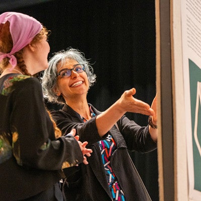 A faculty and student engaged in conversation about the student's Undergraduate Research Symposium poster presenation.